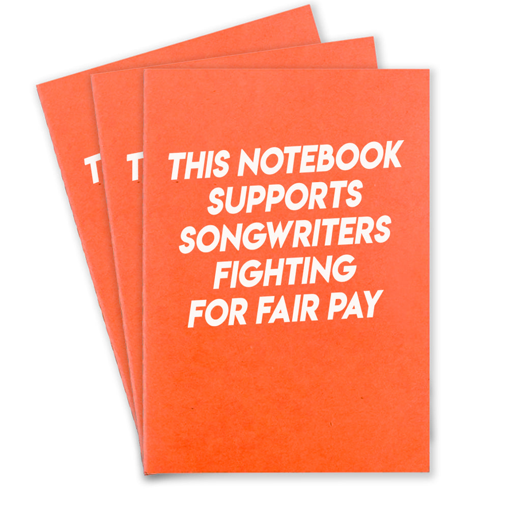 3 orange notebooks that says "This Notebook supports songwriters fighting for fair pay" in white texton the front