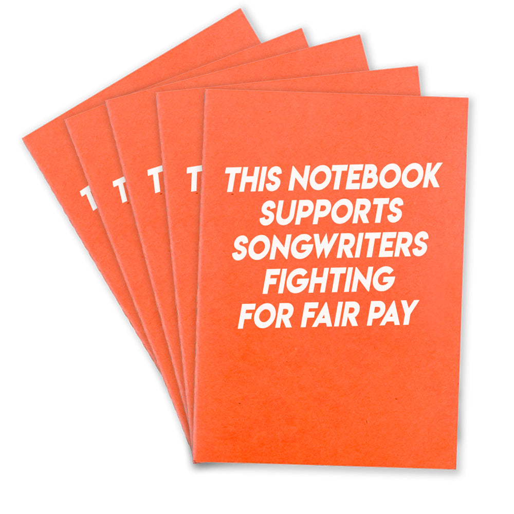 5 orange notebooks that says "This Notebook supports songwriters fighting for fair pay" in white texton the front