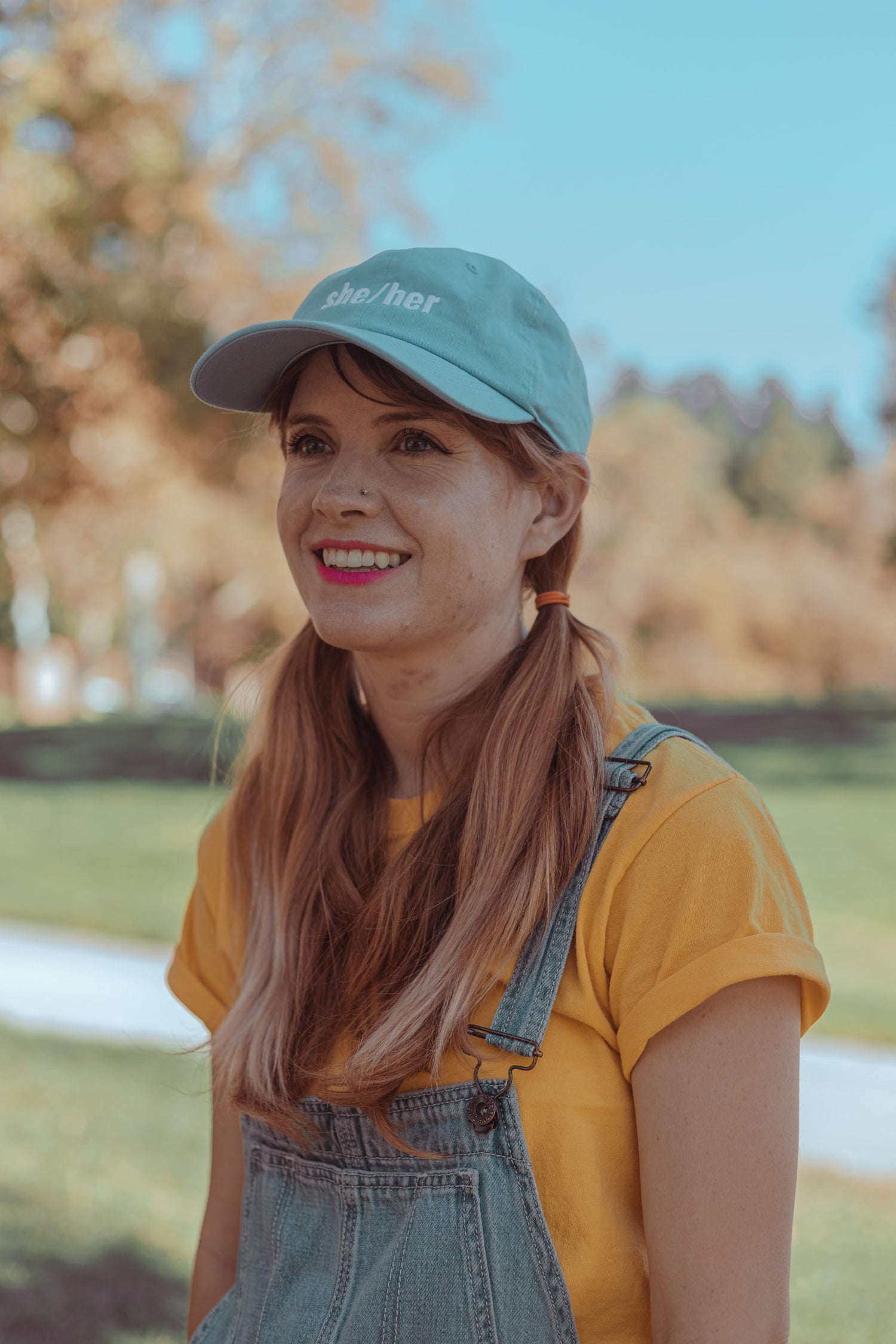 A woman wearing a she/her baby blue hat