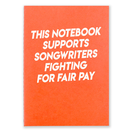1 orange notebook that says "This Notebook supports songwriters fighting for fair pay" in white texton the front