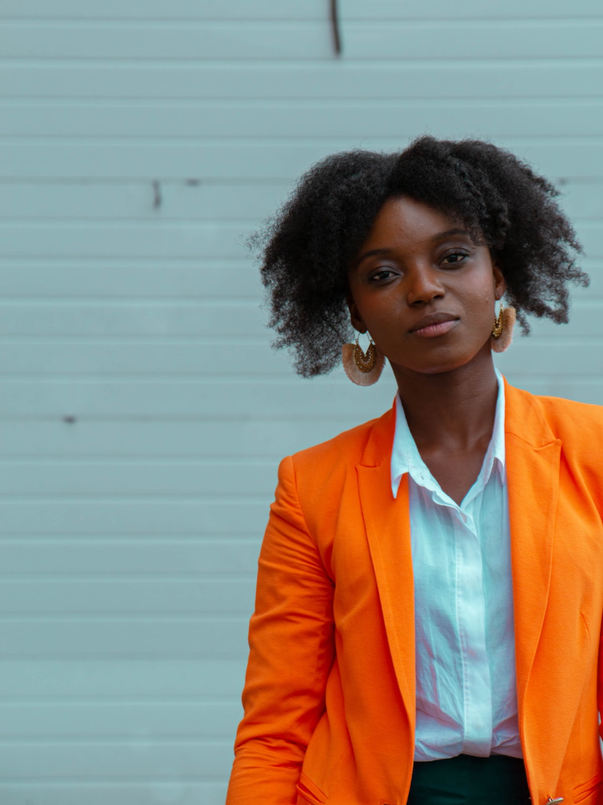 A woman in front of a blue wall wearing a bright orange port coat